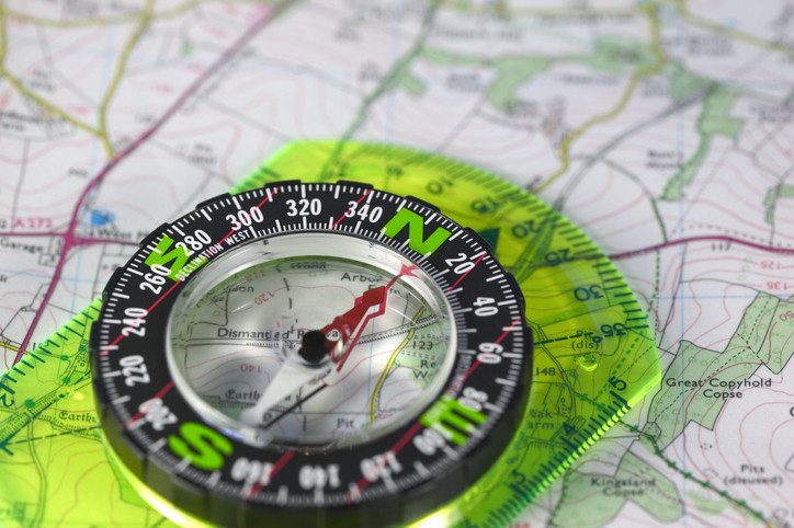 Translucent green compass above a map with the red magnetic needle pointing north